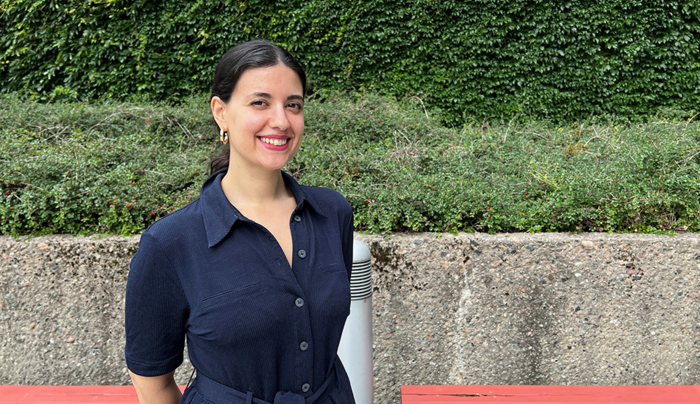 Eirini Tsirvouli outside with a wall and green bushes behind her
