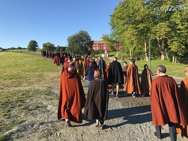 Many people walking outside wearing long capes