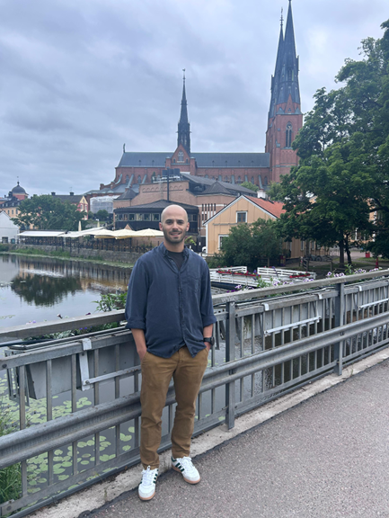 Miguel Teixeira is standing on a bridge, in the background is a river and a church