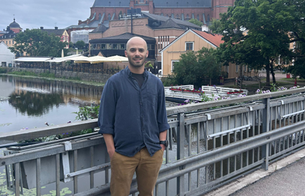 Miguel Teixeira is standing on a bridge, in the background is a river and a church tower.